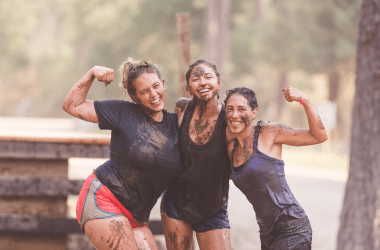 Three women covered in mud from a mud run charity race